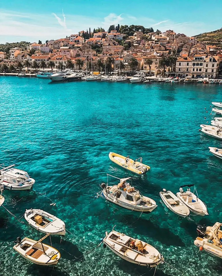Promenada i marina na wyspie Hvar z zacumowanymi łodziami w słoneczny dzień.