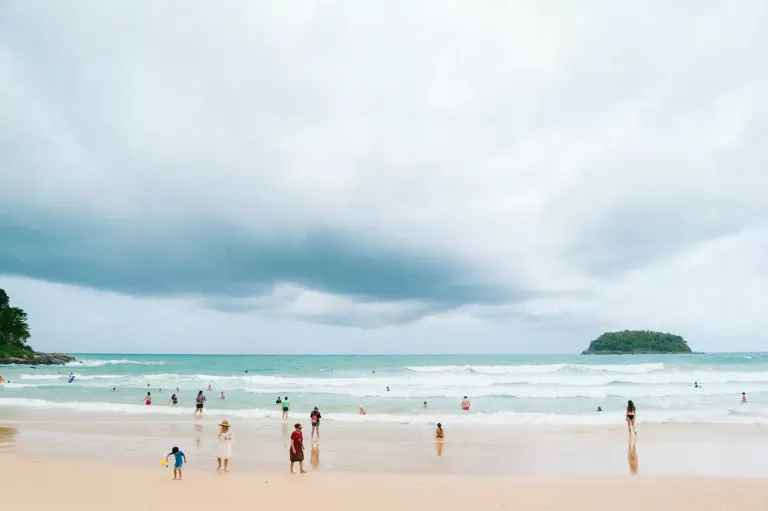 Plaża w Phuket o zachodzie słońca z rodziną bawiącą się w piasku