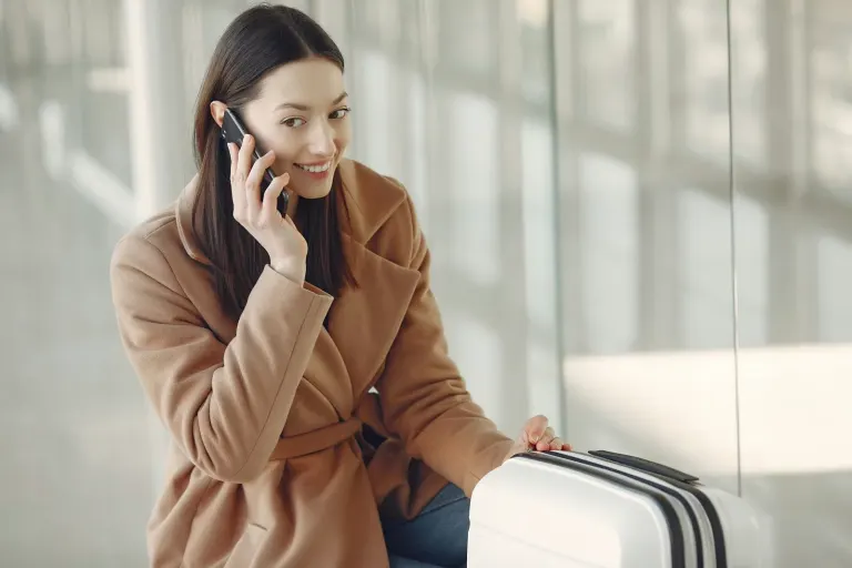 Podróżna z walizką rozmawia przez telefon w terminalu lotniczym