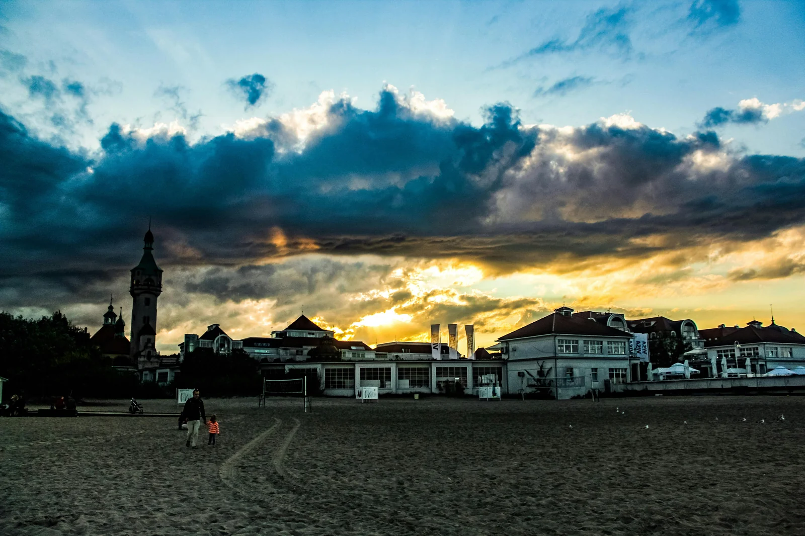 Rodzina spacerująca po plaży o zachodzie słońca