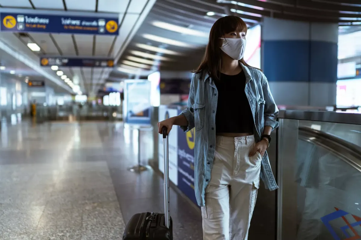 Pasażerka w maseczce przechodząca przez terminal przylotów w Bangkoku