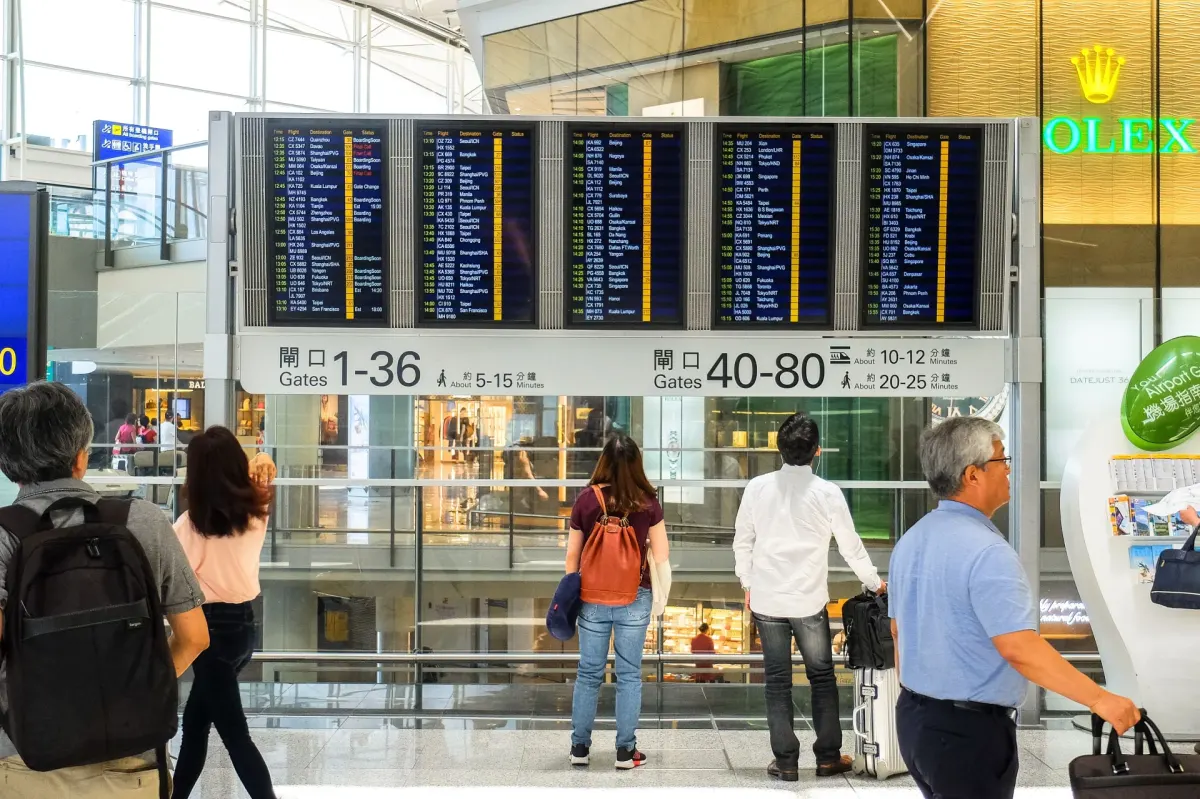 Pasażerowie sprawdzający tablicę odlotów w terminalu lotniska